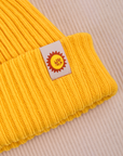 Ribbed Beanie in Golden Yellow close up of sun baby tag