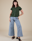 Alex is wearing Pantry Button-Up in Swamp Green and light wash Indigo Wide Leg Trousers