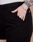 Close up of Sydney's hand in the front pocket of Classic Work Shorts in Basic Black