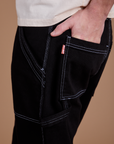 Close up of Quinn's hand in the back pocket of Carpenter Jeans in Black