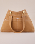 Overall Handbag in Tan with handle strap hanging down front
