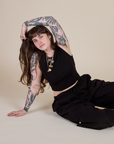 Sydney is sitting on the floor and wearing Muscle Tee in Basic Black and black Drop Pocket Cargo Pants