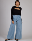 Tiara wearing the Black Porthole Long Sleeve Tee tucked into the Light Wash Wide Leg Denim Trousers