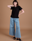 Alex is 5'8" and wearing P Burly Tee in Basic Black paired with light wash Indigo Wide Leg Trousers