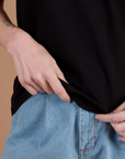 Burly Tee in Basic Black bottom close up with Alex holding the hem