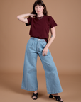 Alex is wearing Burly Tee in Red Wine tucked into light wash Indigo Wide Leg Trousers