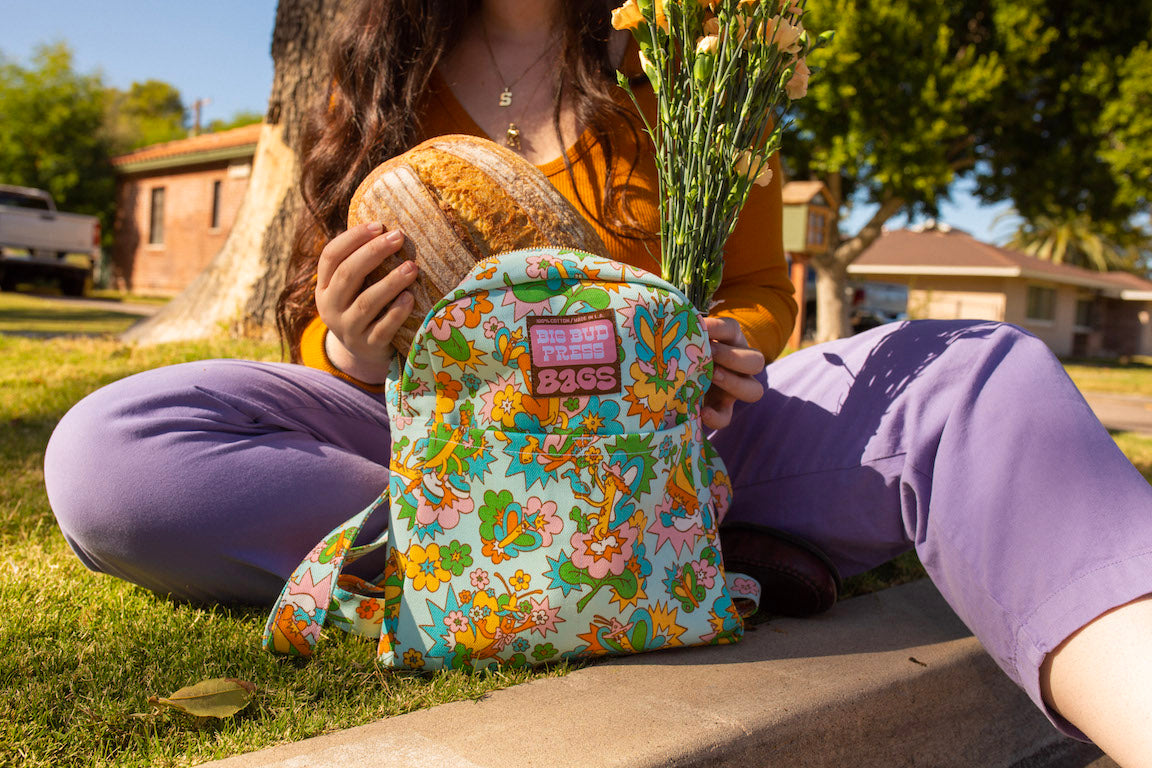 Mini Backpack in Butterfly Bash on Sydney wearing Long Sleeve V-Neck Tee in Spicy Mustard and Trousers in Faded Grape.