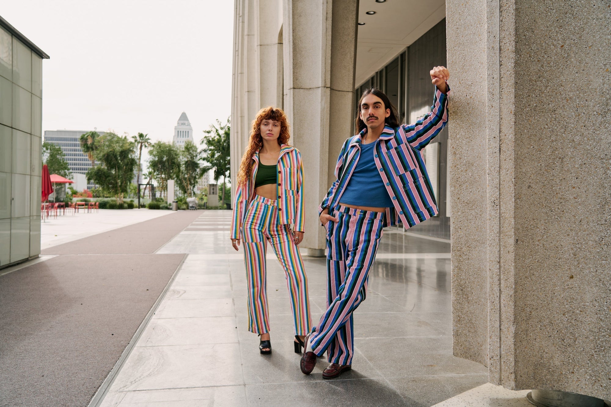Anthony is wearing Stripe Work Jacket and Pants in Pacific Stripe. Sadie is wearing Stripe Work Jacket and Pants in Rainbow Stripe