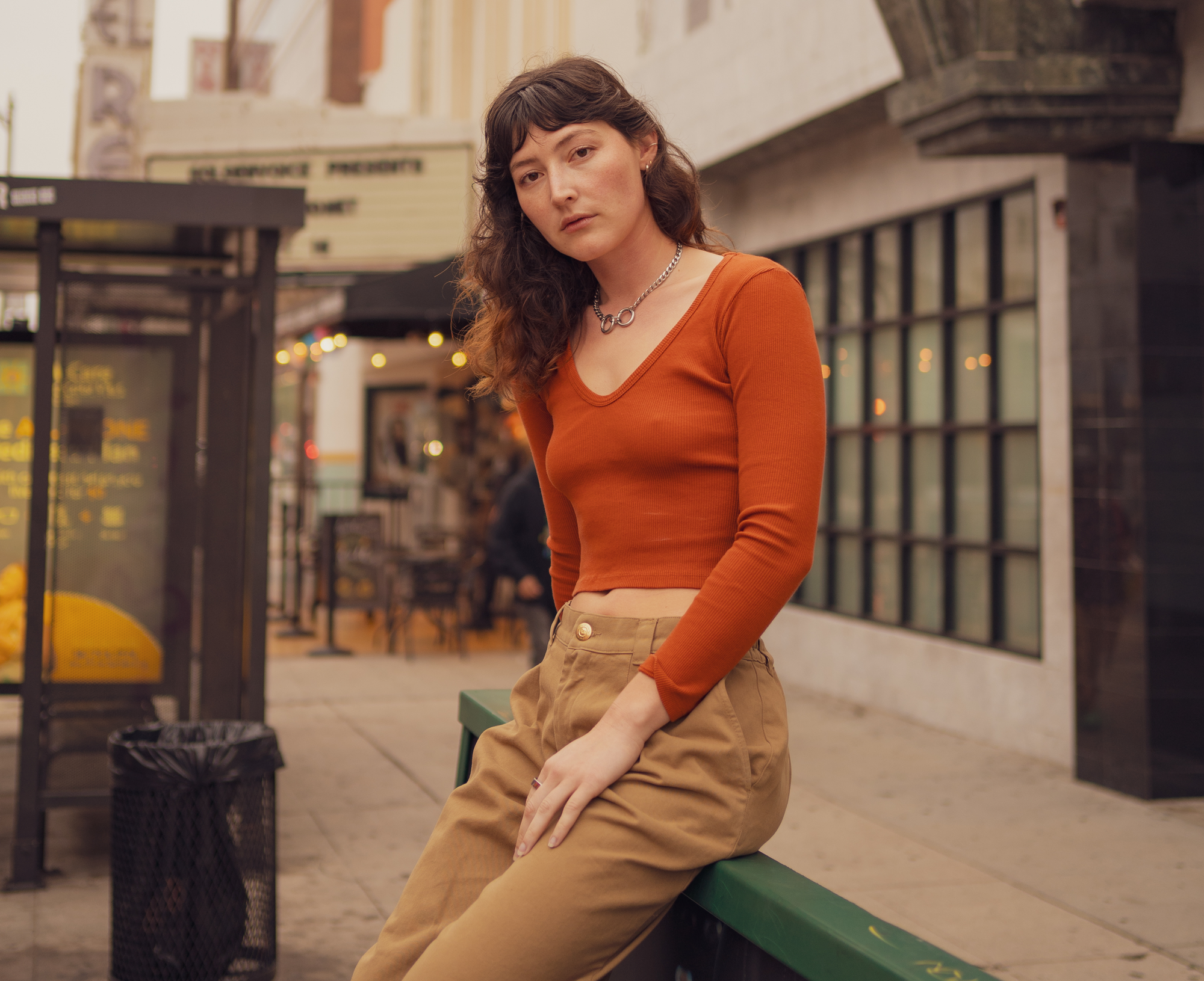 Alexandra Skye is wearing Mid-Rise Pleated Trousers in Desert Brown and Long Sleeve V-Neck Tee in Burnt Terracotta