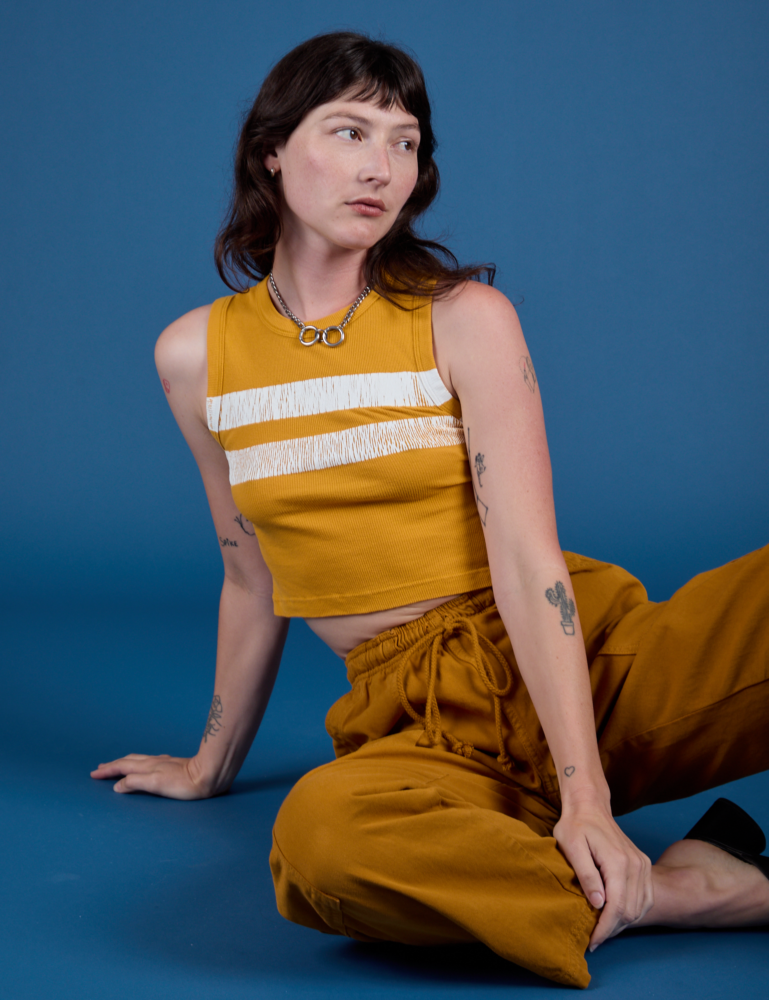 Alex is 5’8” and wearing P Painted Muscle Tee in Mustard Yellow