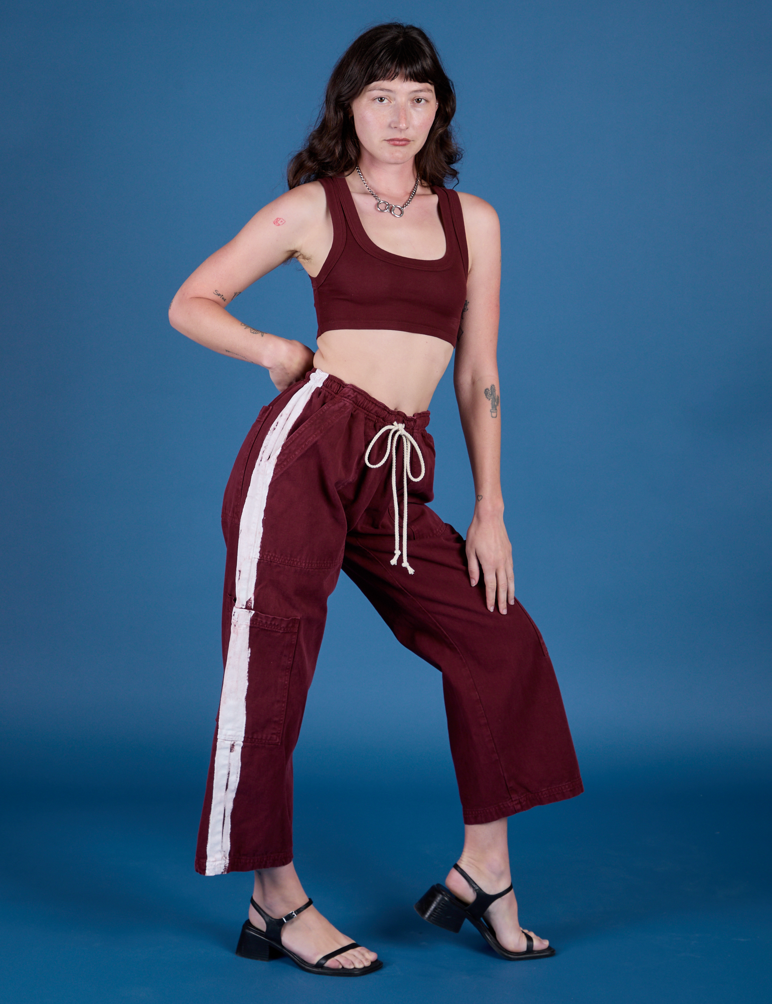 Alex is 5’8” and wearing XXS Painted Drop Pocket Cargo Pants in Red Wine paired with Mini Tank in Red Wine
