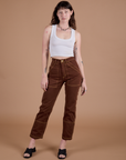 Alex is 5’8” and wearing XXS Carpenter Jeans in Fudgesicle Brown paired with a Cropped Tank in Vintage Tee White