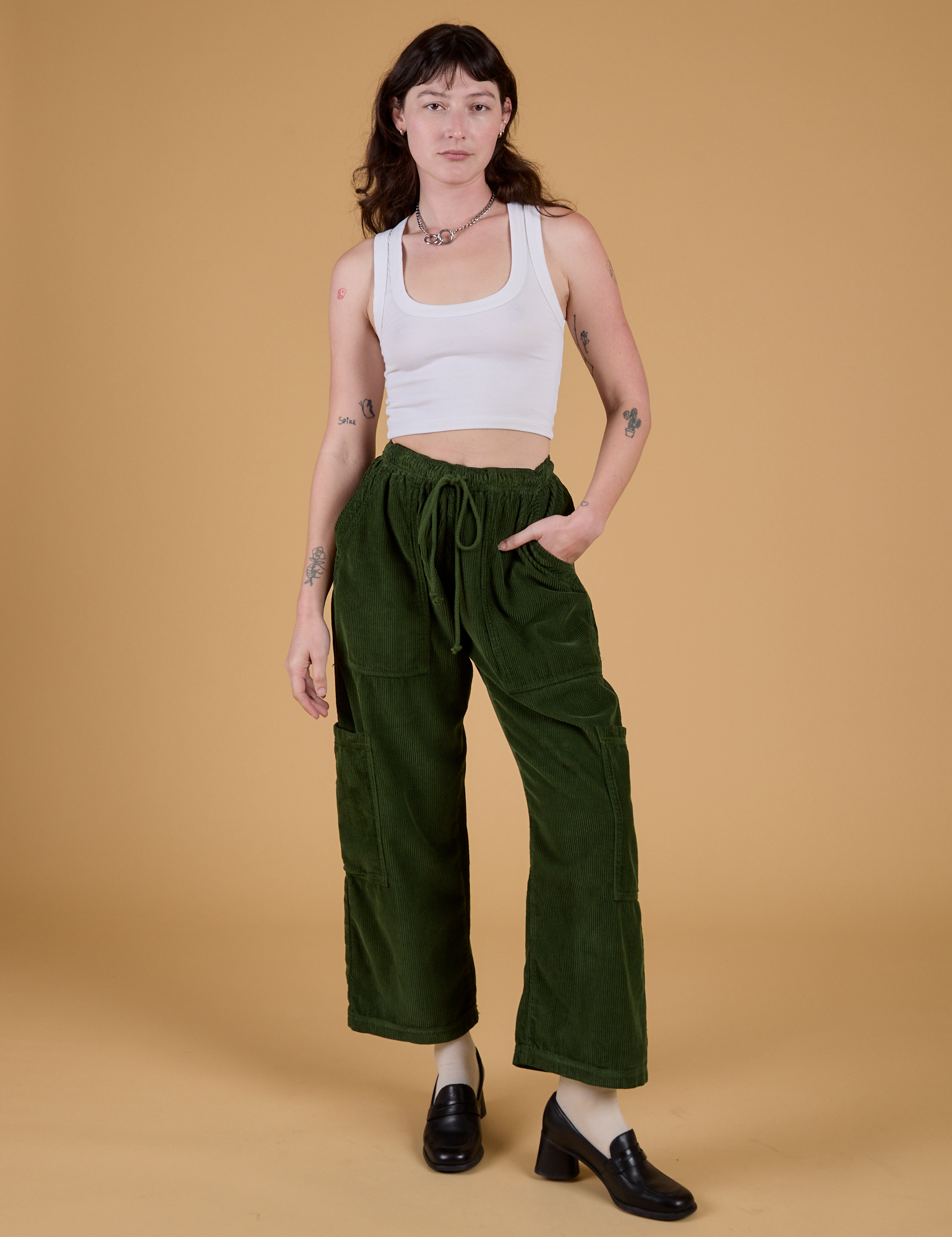 Alex is 5’8” and wearing XXS Corduroy Drop Pocket Cargo Pants in Evergreen paired with a Cropped Tank in Vintage Tee White