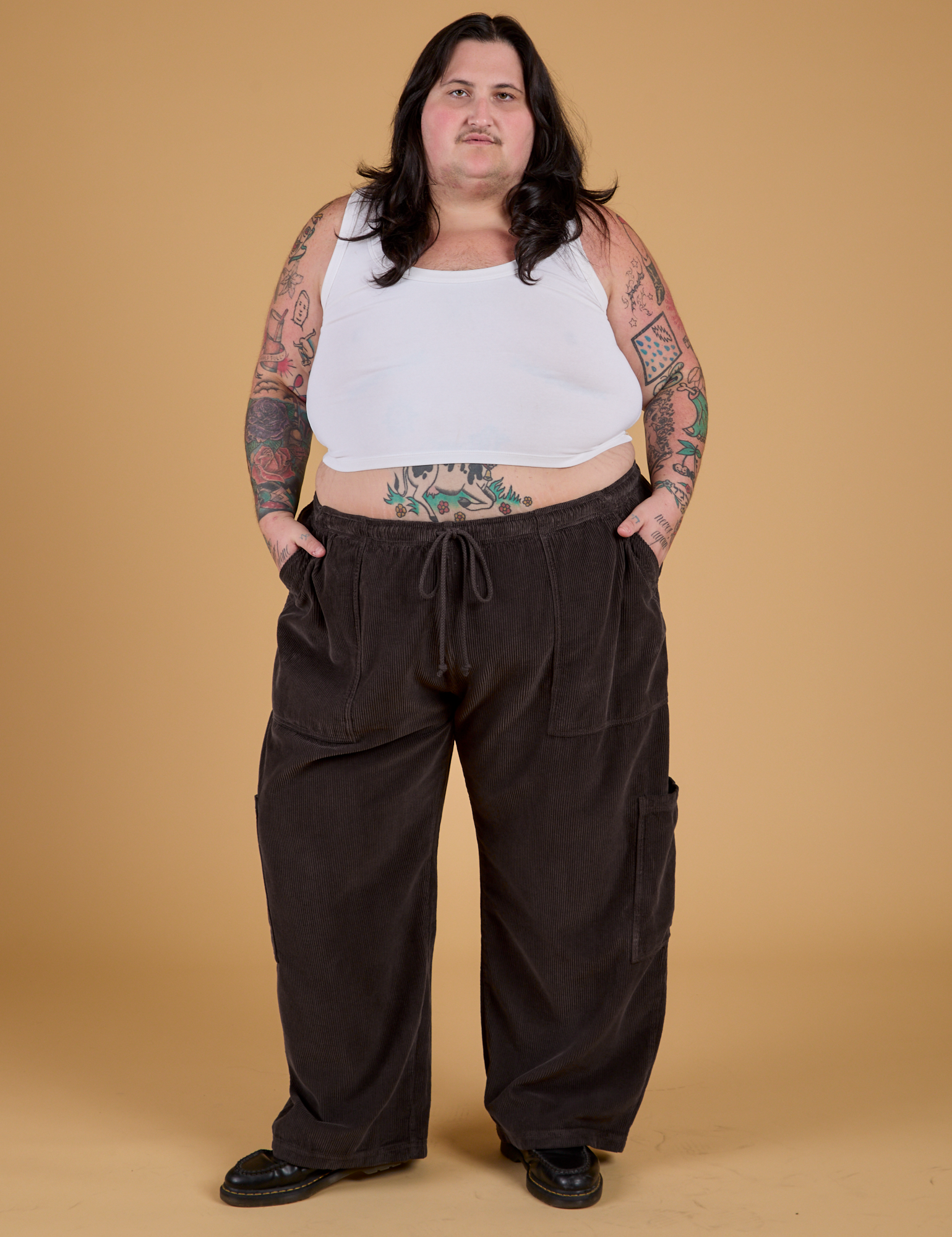 Sam is 5'10" and wearing 2XL Corduroy Drop Pocket Cargo Pants in Espresso Brown paired with a Cropped Tank in Vintage Tee White