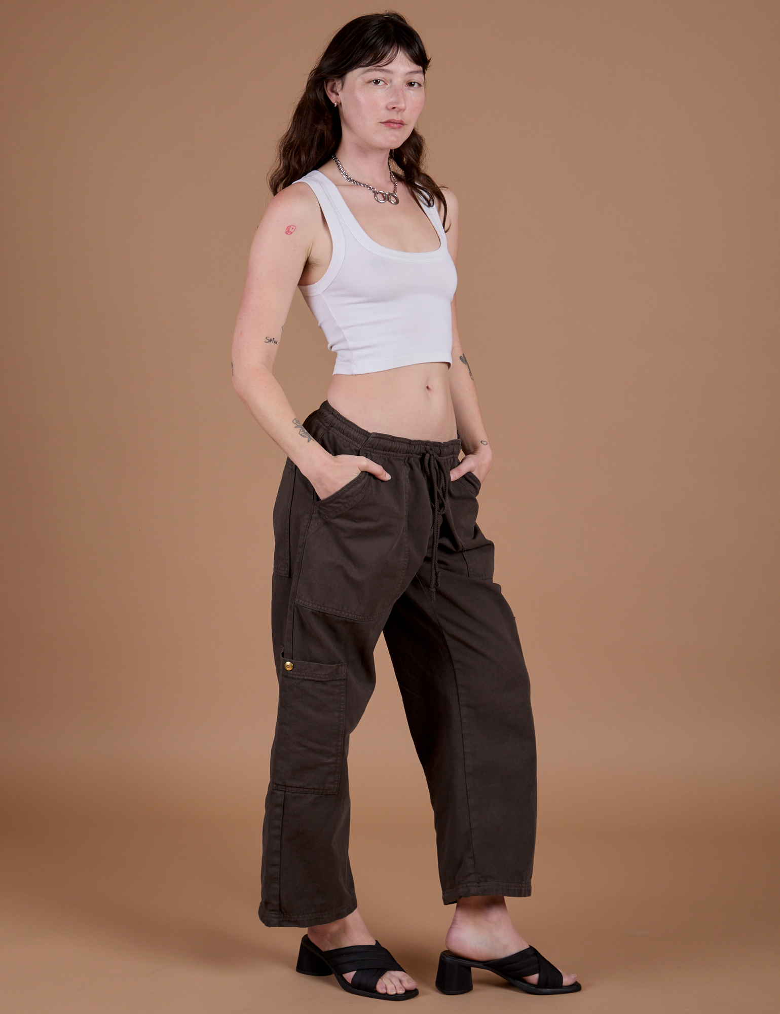 Alex is 5’8” and wearing XXS Drop Pocket Cargo Pants in Espresso Brown paired with a vintage tee white Cropped Tank