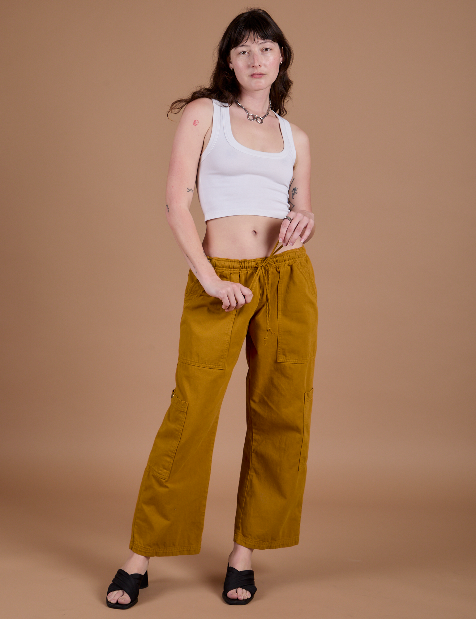 Alex is 5’8” and wearing XXS Drop Pocket Cargo Pants in Spicy Mustard  paired with vintage tee white Cropped Tank