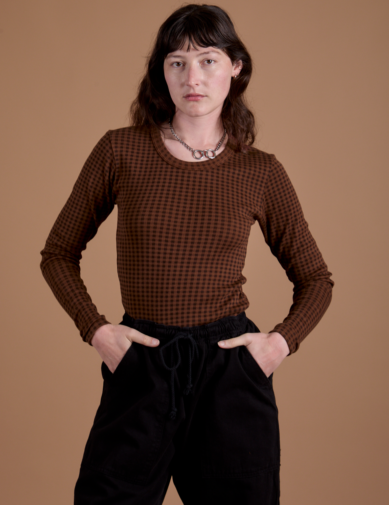Alex is 5’8” and wearing XP Gingham Long Sleeve Baby Tee in Fudgesicle Brown