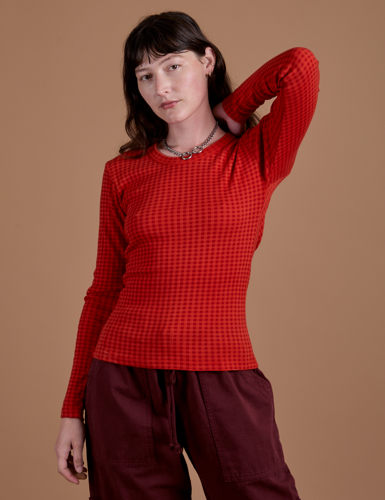 Alex is 5’8” and wearing XP Gingham Long Sleeve Baby Tee in Mustang Red