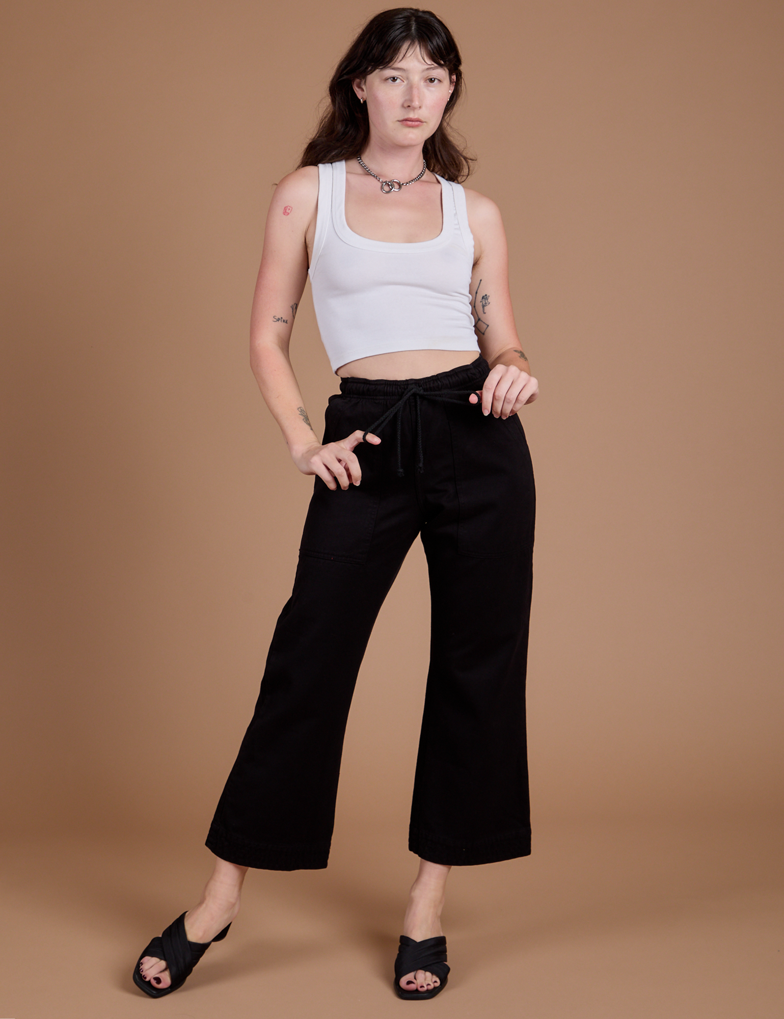 Alex is 5'8" and wearing XXS Organic Action Pants in Basic Black paired with a vintage tee white Cropped Tank