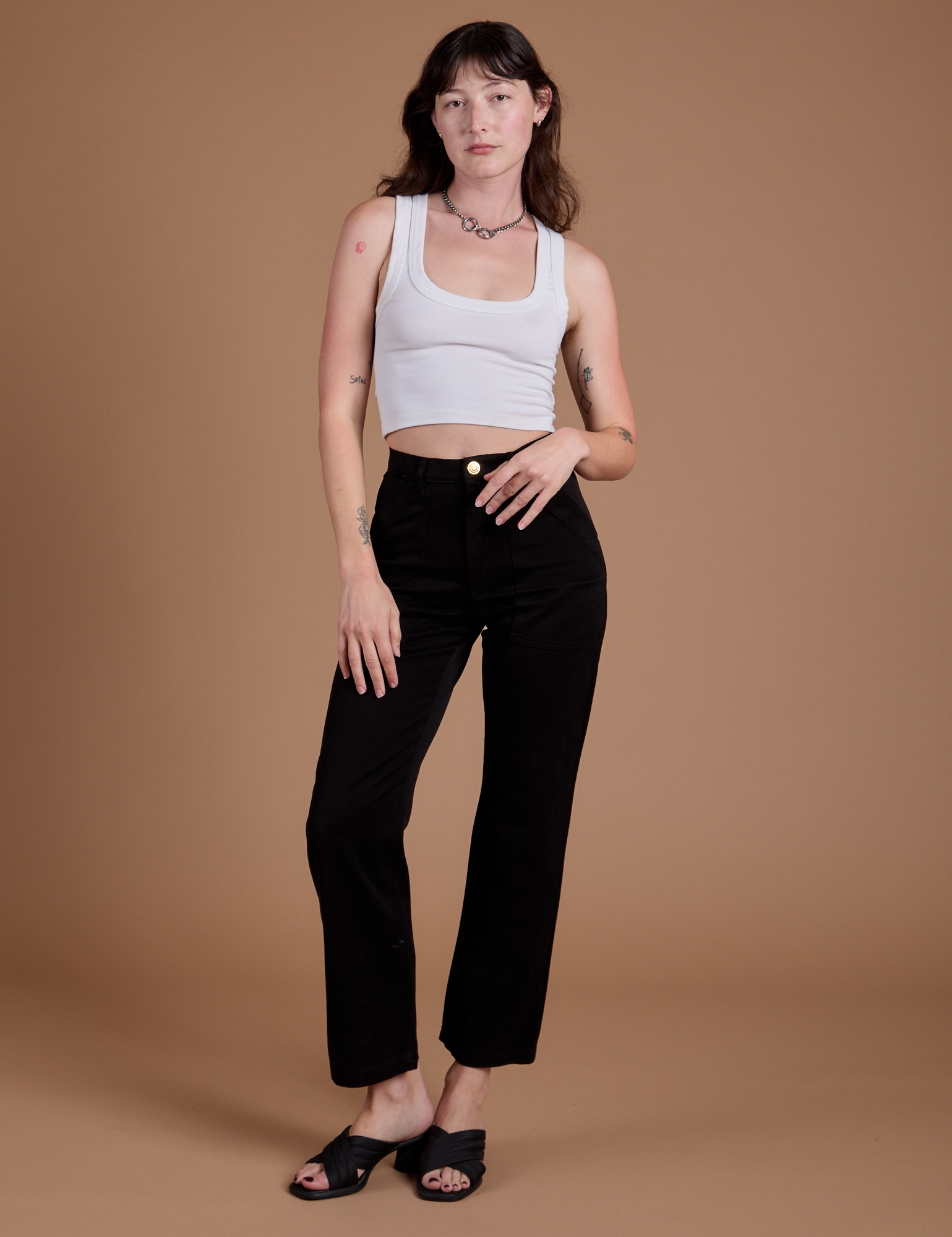 Alex is 5'8" and wearing XXS Organic Work Pants in Basic Black paired with a vintage tee white Cropped Tank