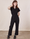 Hana is 5’3” and wearing XXS Petite Short Sleeve Jumpsuit in Basic Black