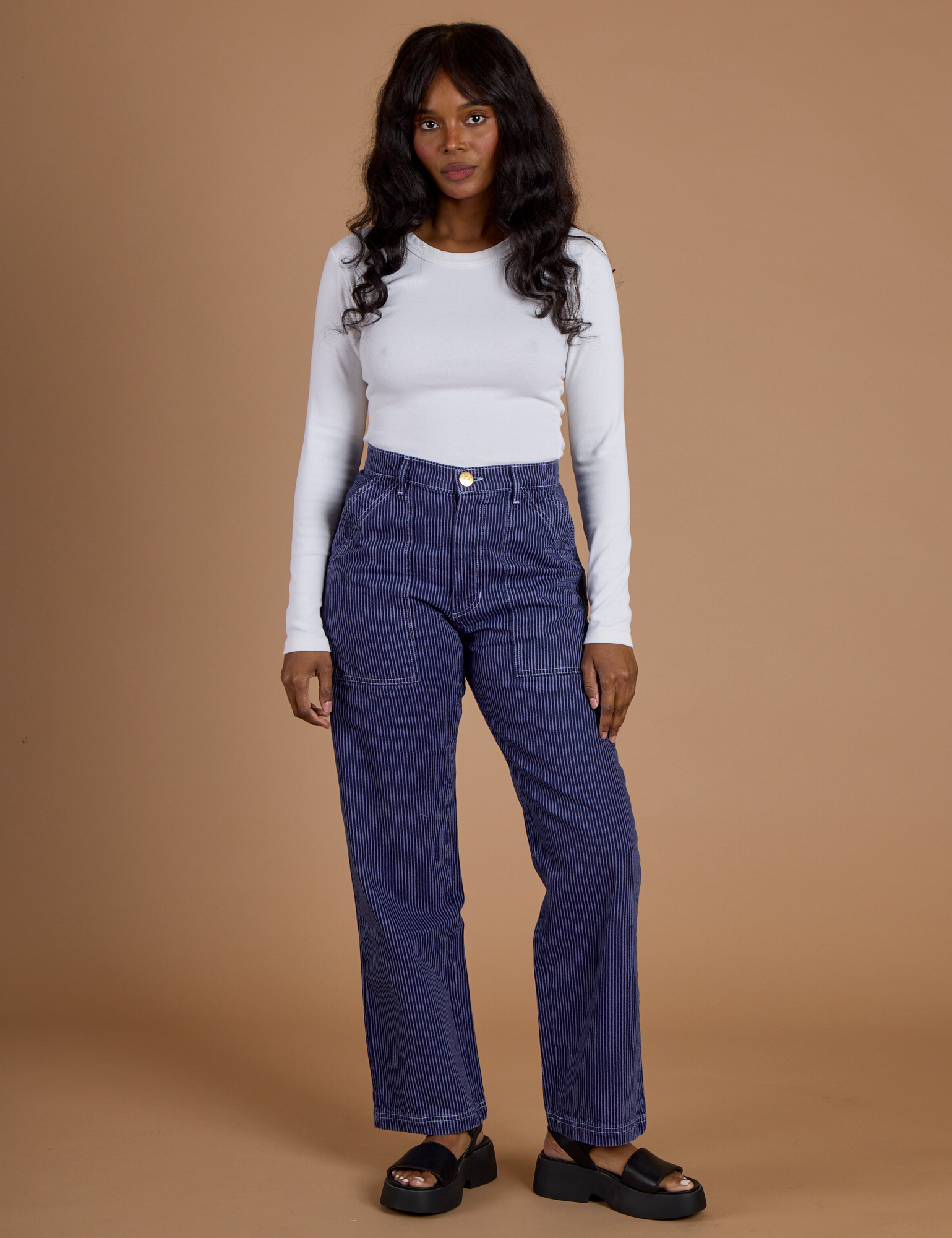 Kandia is 5’3” and wearing XS Railroad Denim Work Pants in Faded Grape Overdye paired with vintage tee white Long Sleeve Baby Tee