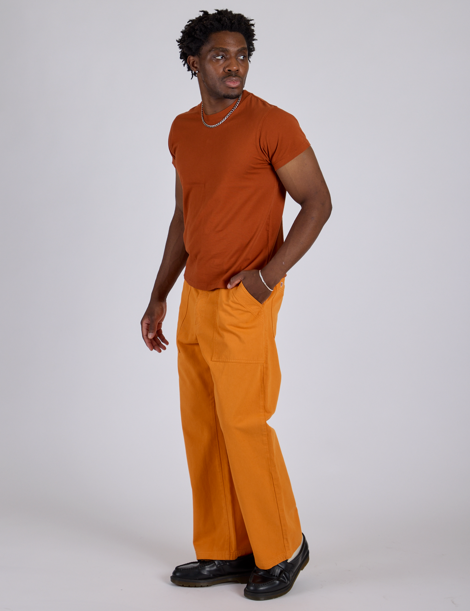 Angled front view of Work Pants in Creamsicle Orange and burnt terracotta Organic Vintage Tee on Isaac