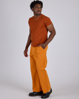 Angled front view of Work Pants in Creamsicle Orange and burnt terracotta Organic Vintage Tee on Isaac