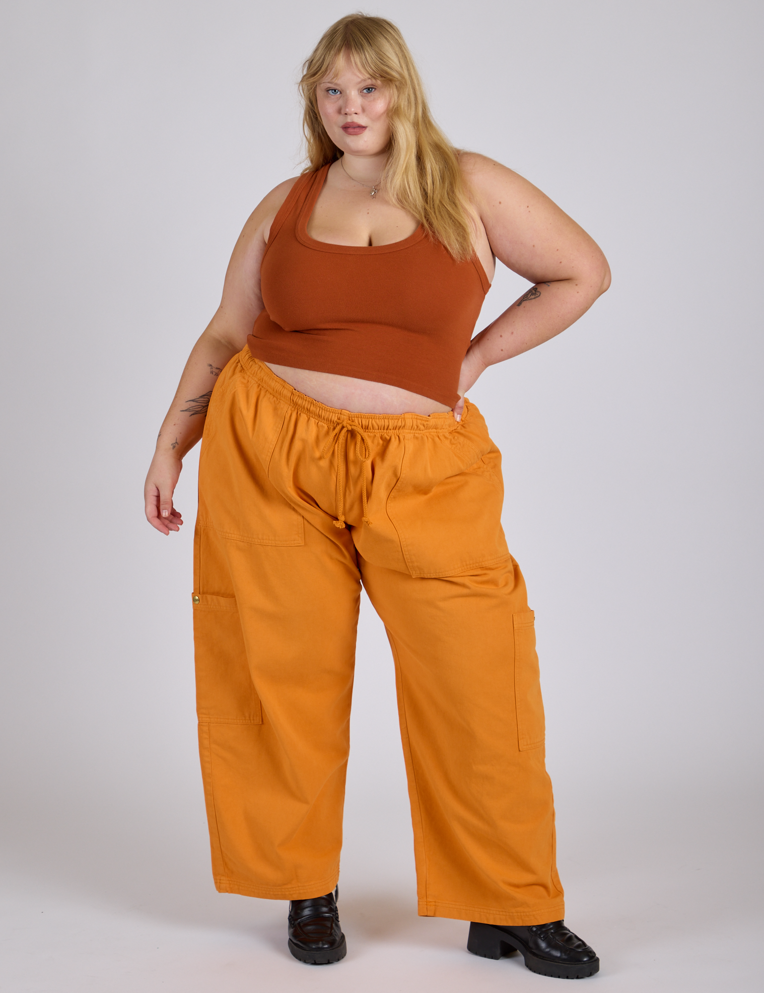 Juliet is 5’7” and wearing 2XL Drop Pocket Cargo Pants in Creamsicle Orange paired with burnt terracotta Cropped Tank