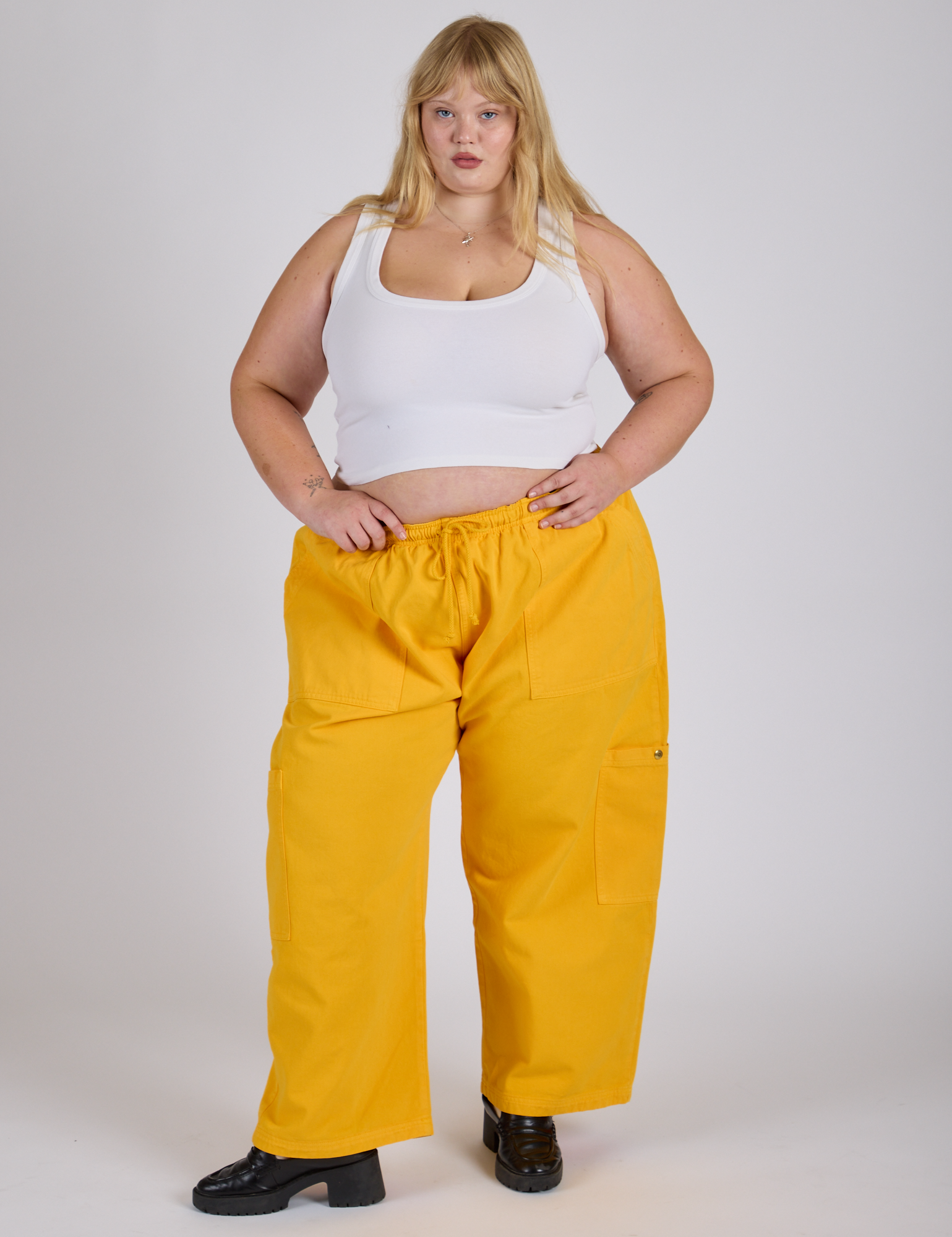 Juliet is 5’7” and wearing 2XL Drop Pocket Cargo Pants in Sunshine Yellow paired with a Cropped Tank in Vintage Tee White