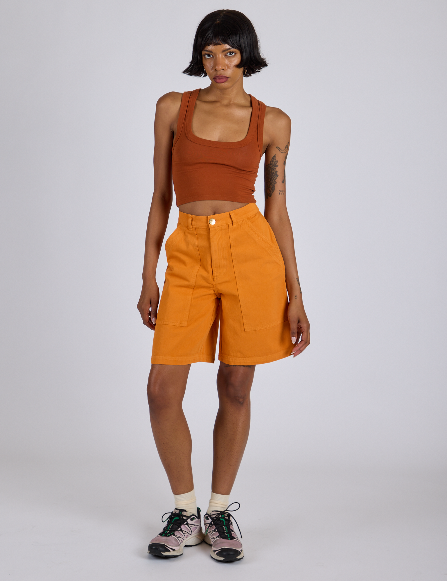 Kira is 5’10” and wearing XS Longline Work Shorts in Creamsicle Orange paired with a burnt terracotta Cropped Tank