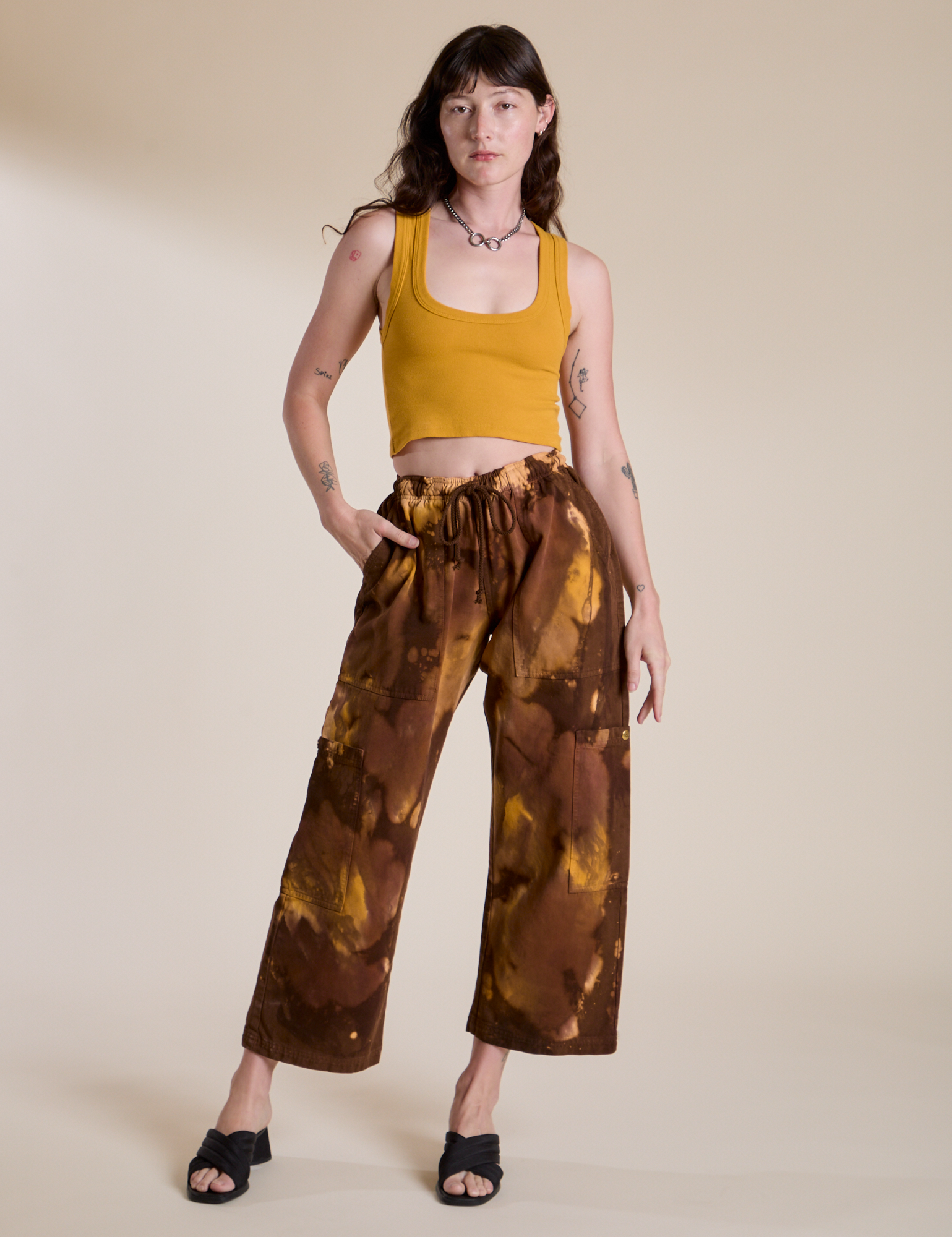 Alex is 5’8” and wearing XXS Magic Waters Drop Pocket Pants in Honey Brown paired with mustard yellow Cropped Tank