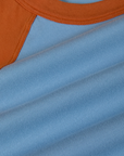 Fabric close up of the Baby Blue/Orange Colorblock Raglan Tee