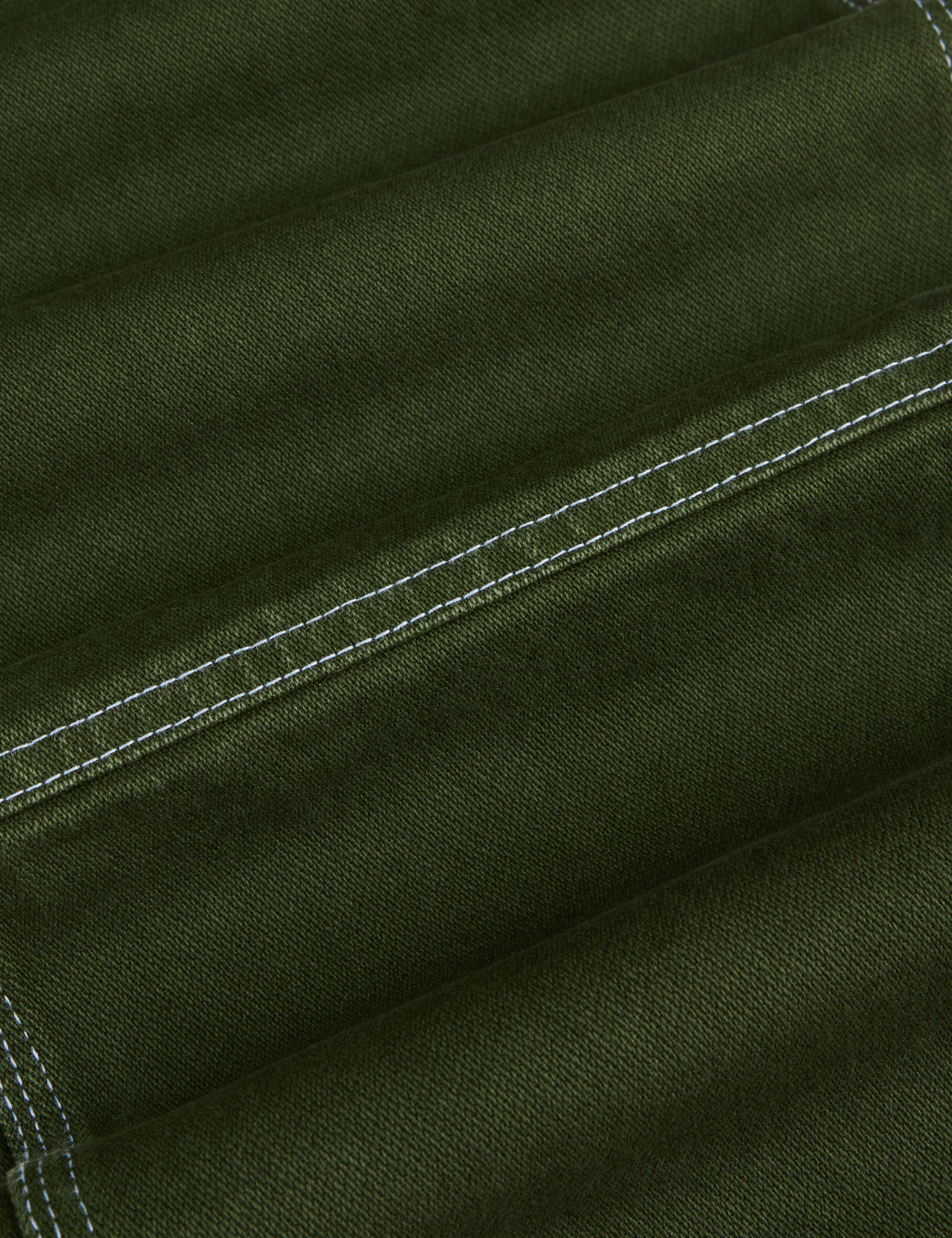 Carpenter Jeans in Evergreen fabric detail close up. White contrast stitching.