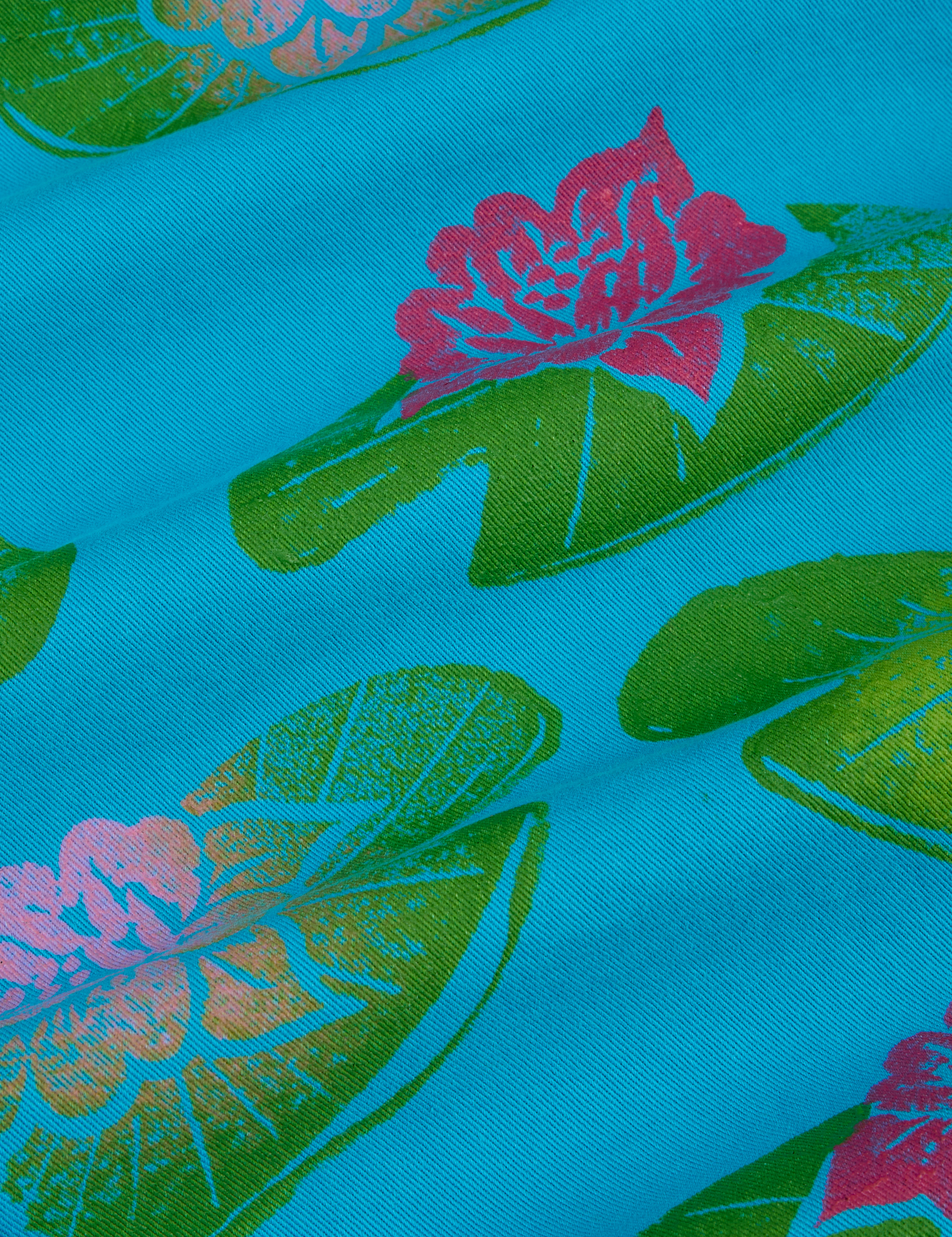 Paintstamped Work Pants in Lilypad fabric close up. Green stamped lilypads with pink flowers