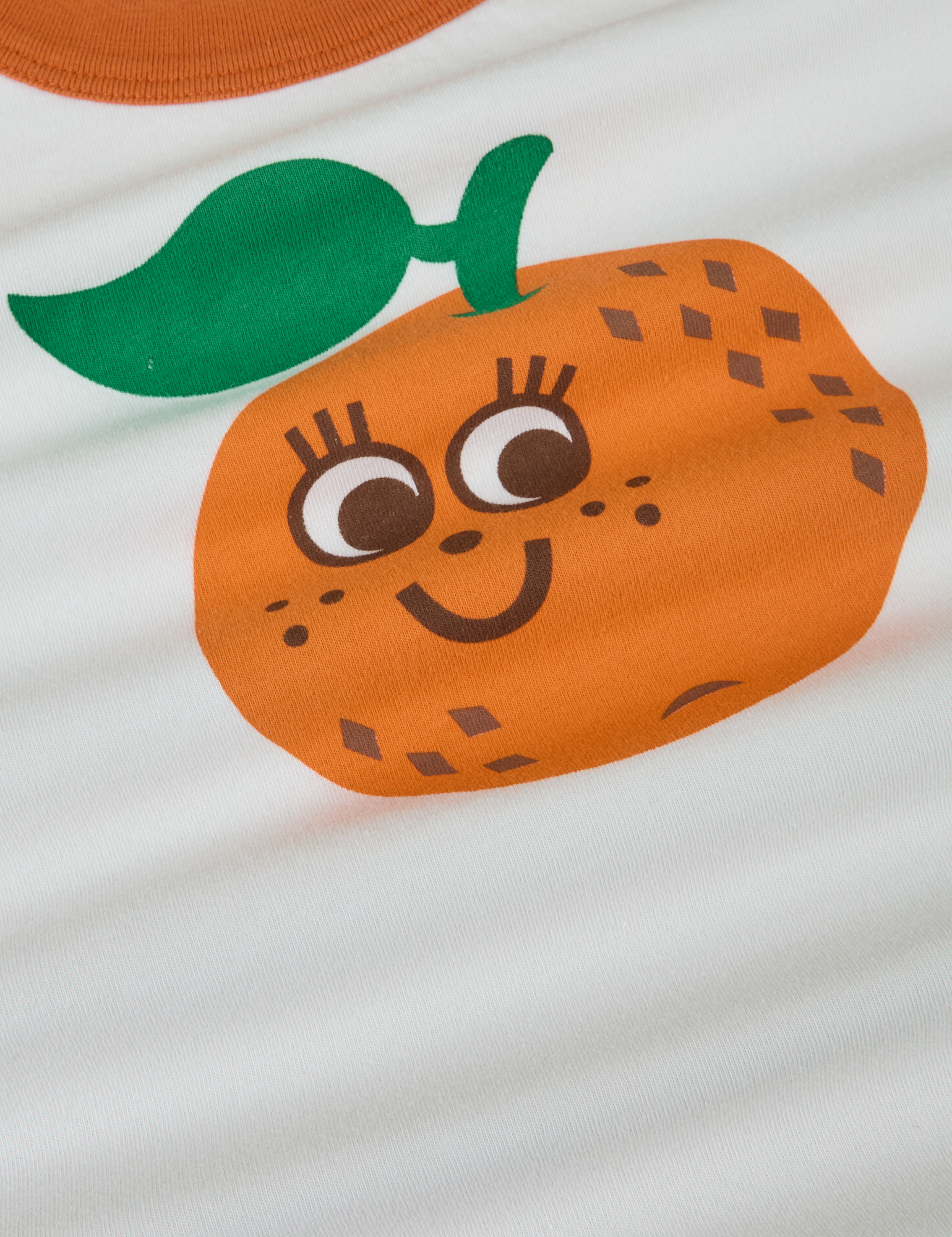 Produce Raglan Tee in Orange close up. Illustrated orange character.