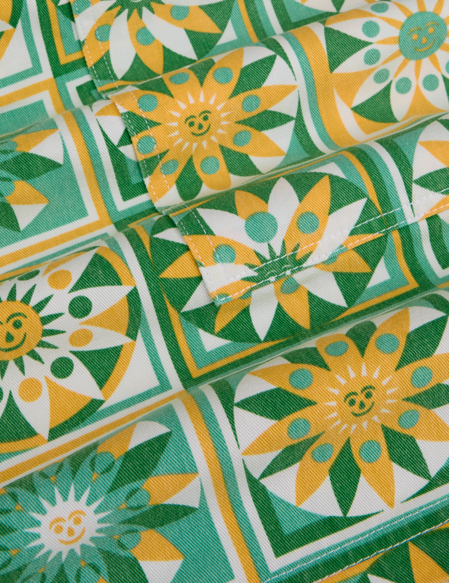 Longline Work Shorts in Spring Quilt Print fabric detail close up. Sun quilt print in green, yellow and white.
