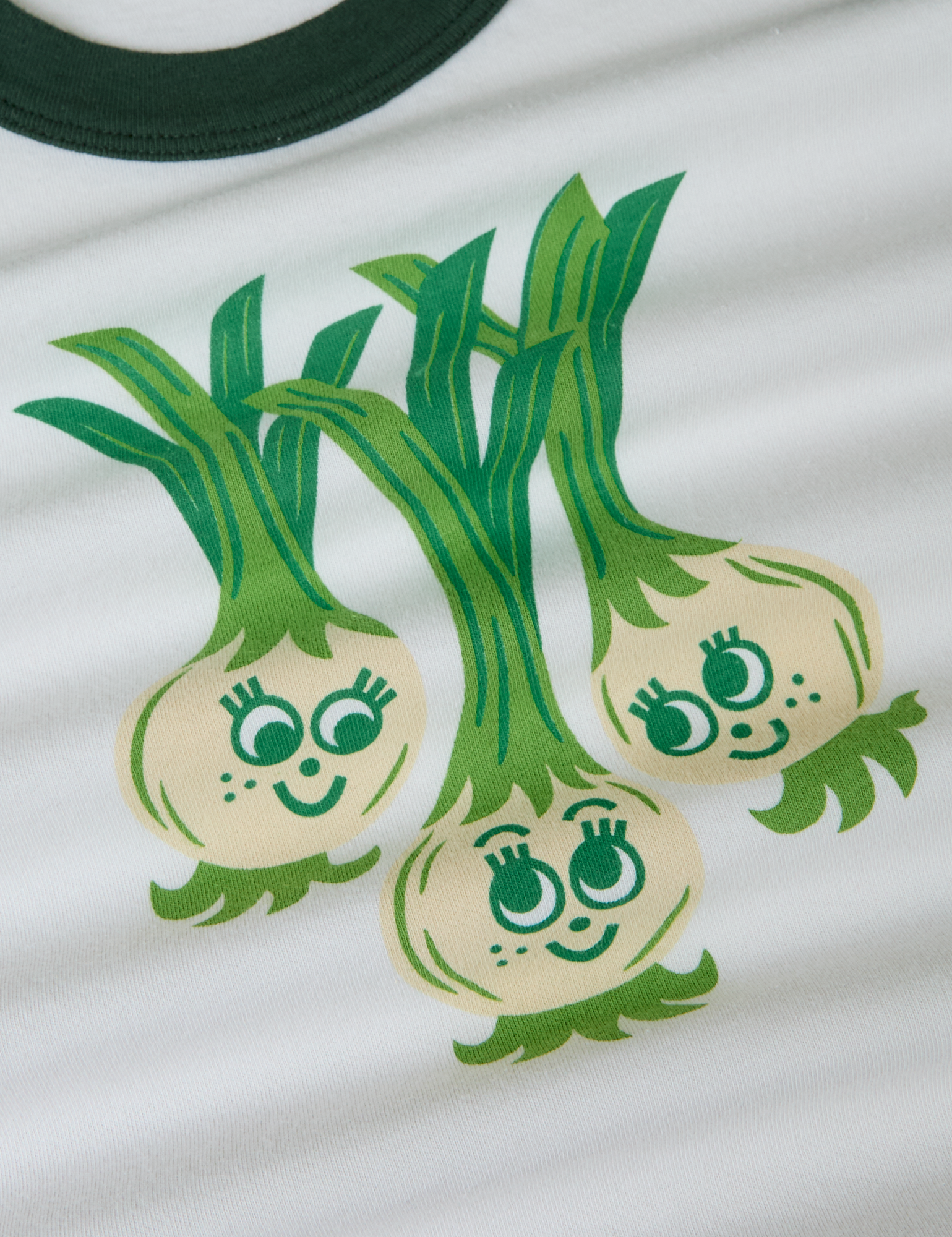 Produce Raglan Tee in Scallions close up. Illustrated scallion characters in green and off-white