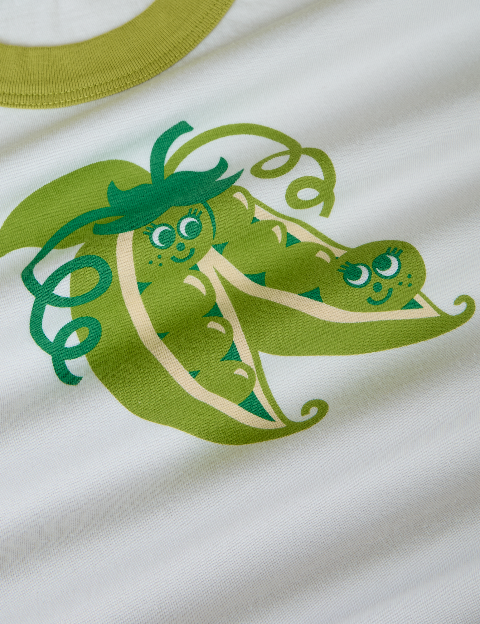 Produce Raglan Tee in Snap Peas close up. Illustrated pair of snap peas in green.