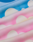 Airbrush Cloud Baby Tee fabric detail close up. Pink and blue background with white clouds