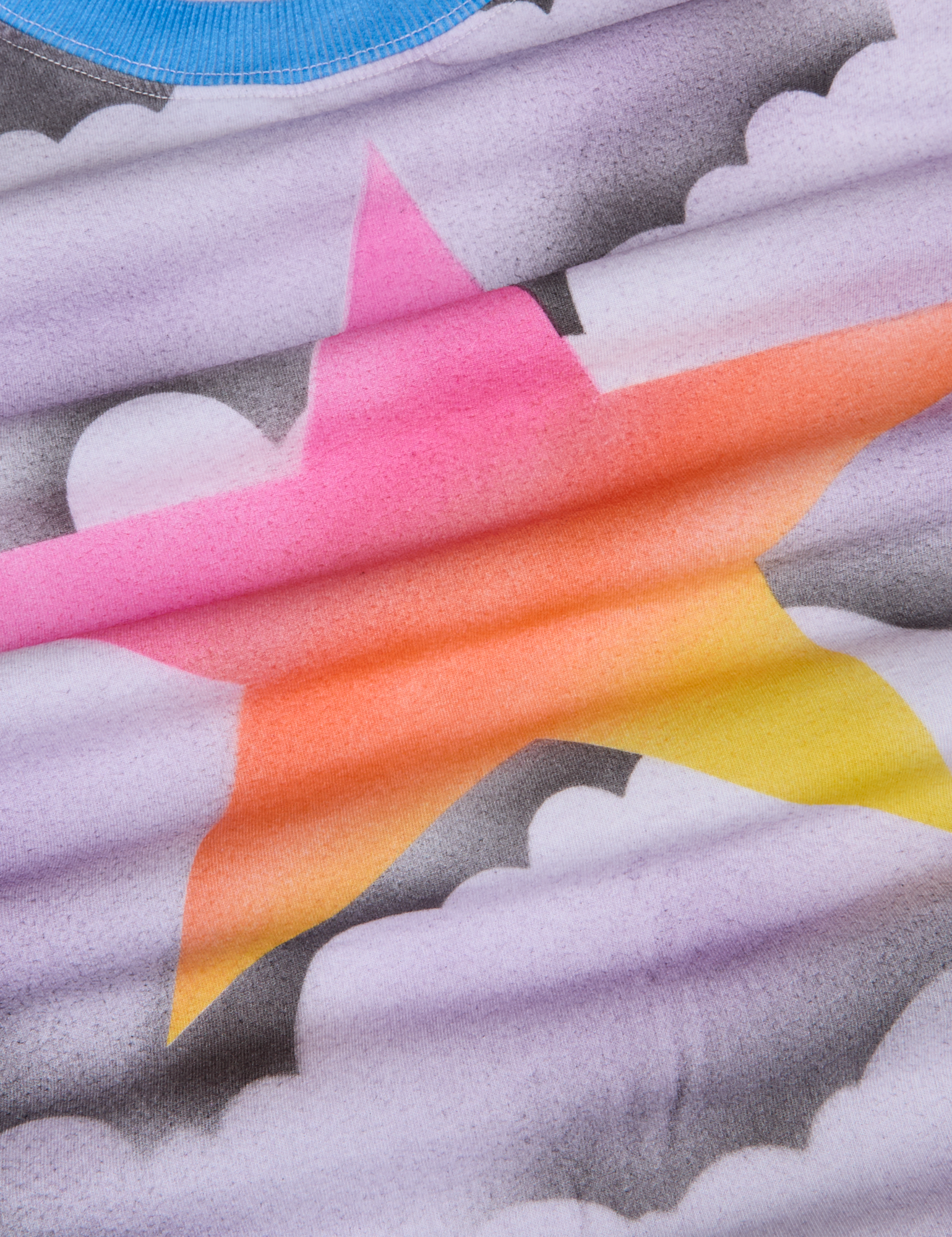 Airbrush Star Vintage Tee fabric detail close up. Airbrushed grey and white clouds with a gradient star in pink, orange and yellow.