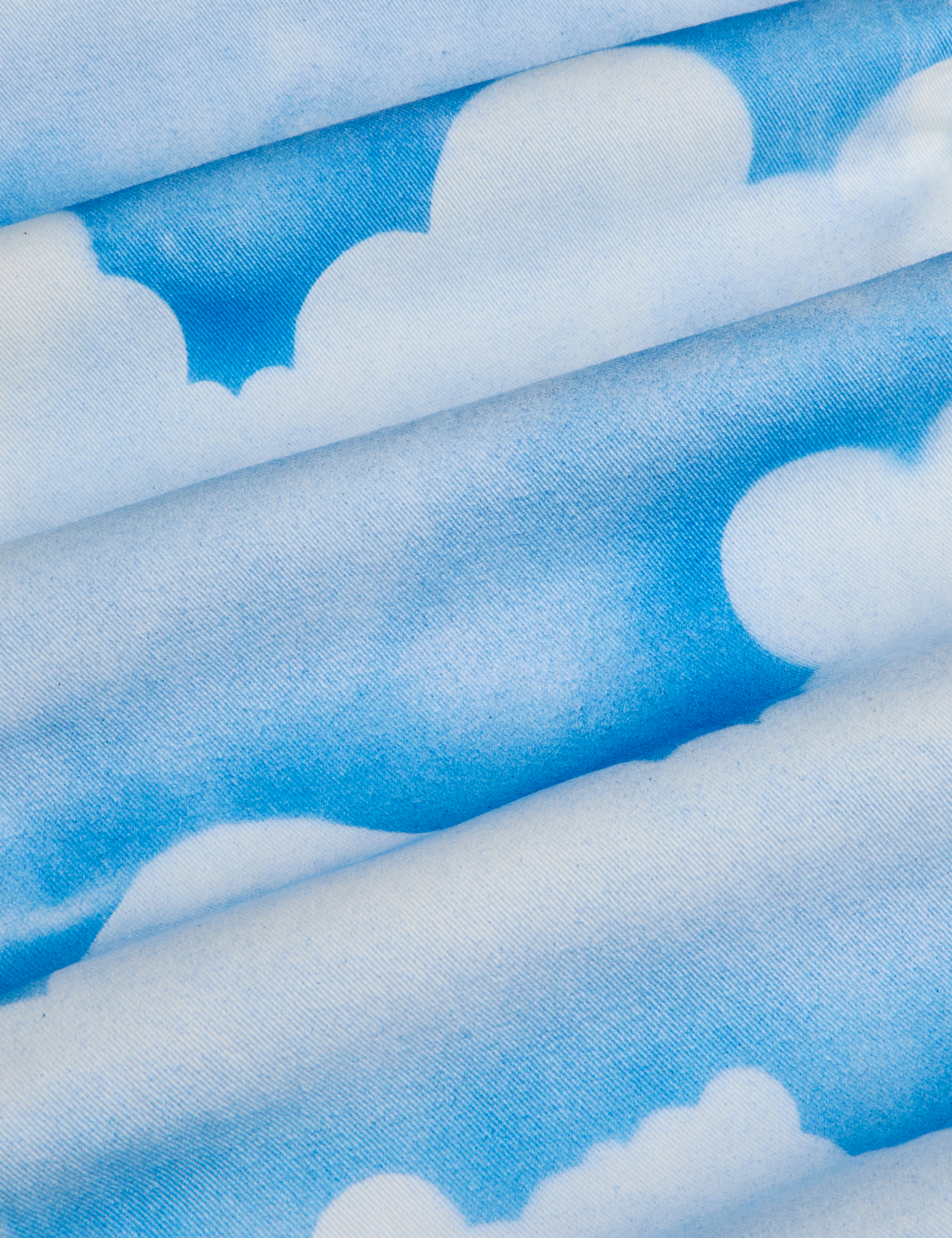 Work Pants in Sunny Cloud Airbrush fabric detail close up. Airbrushed blue skies with white clouds