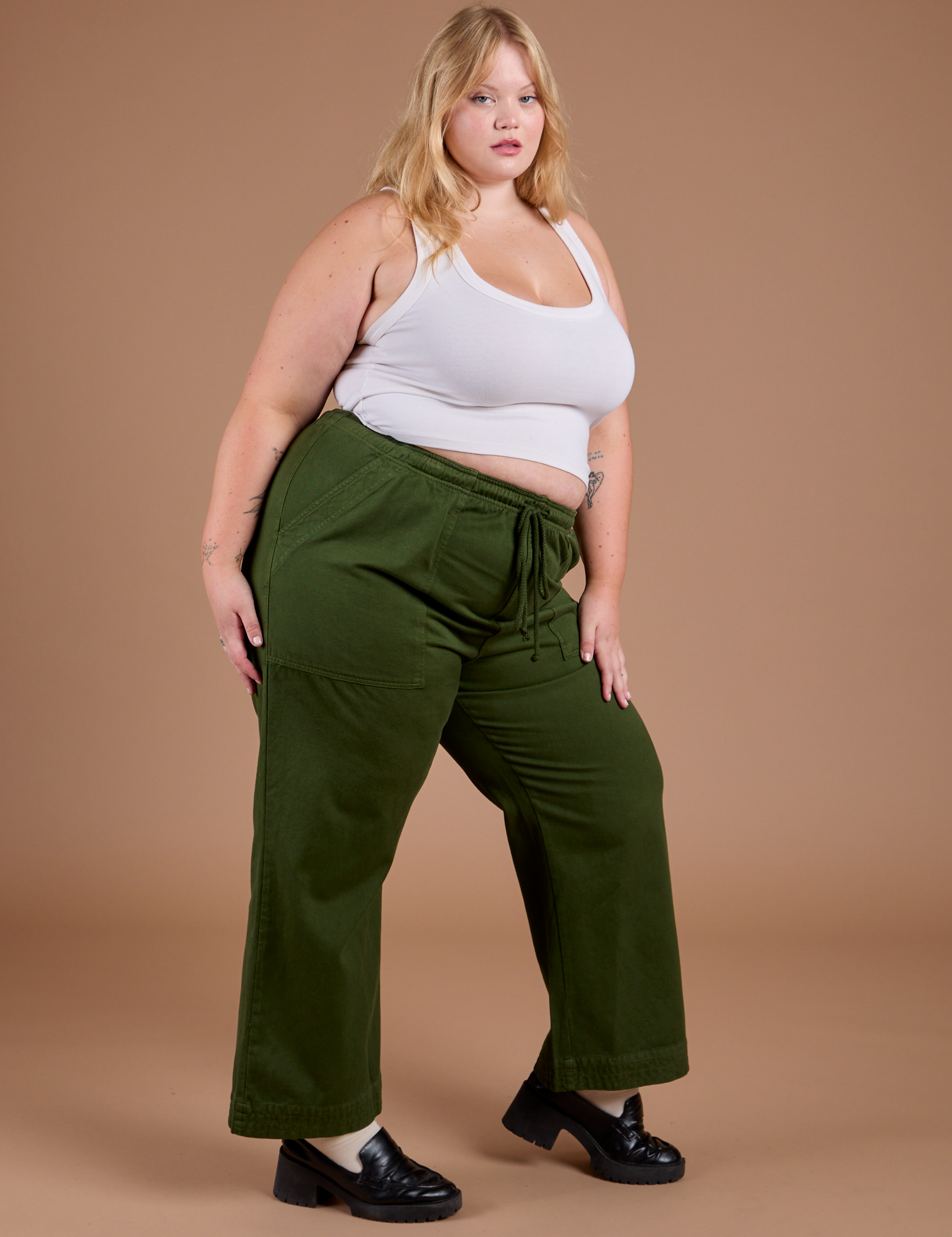 Angled front view of Organic Action Pants in Evergreen and vintage tee white Cropped Tank