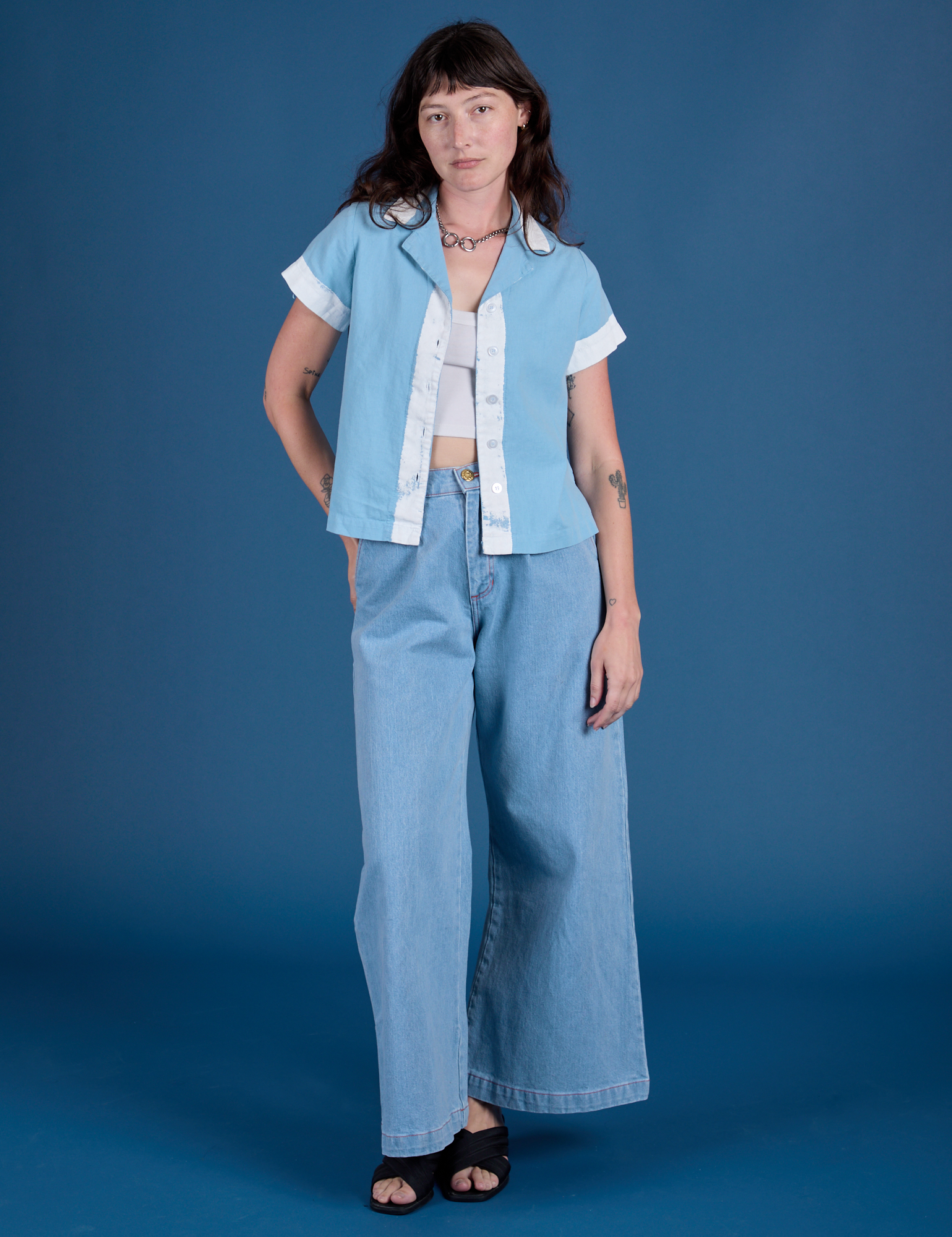 Alex is wearing Painted Pantry Button-Up in Baby Blue and light wash Wide Leg Trousers