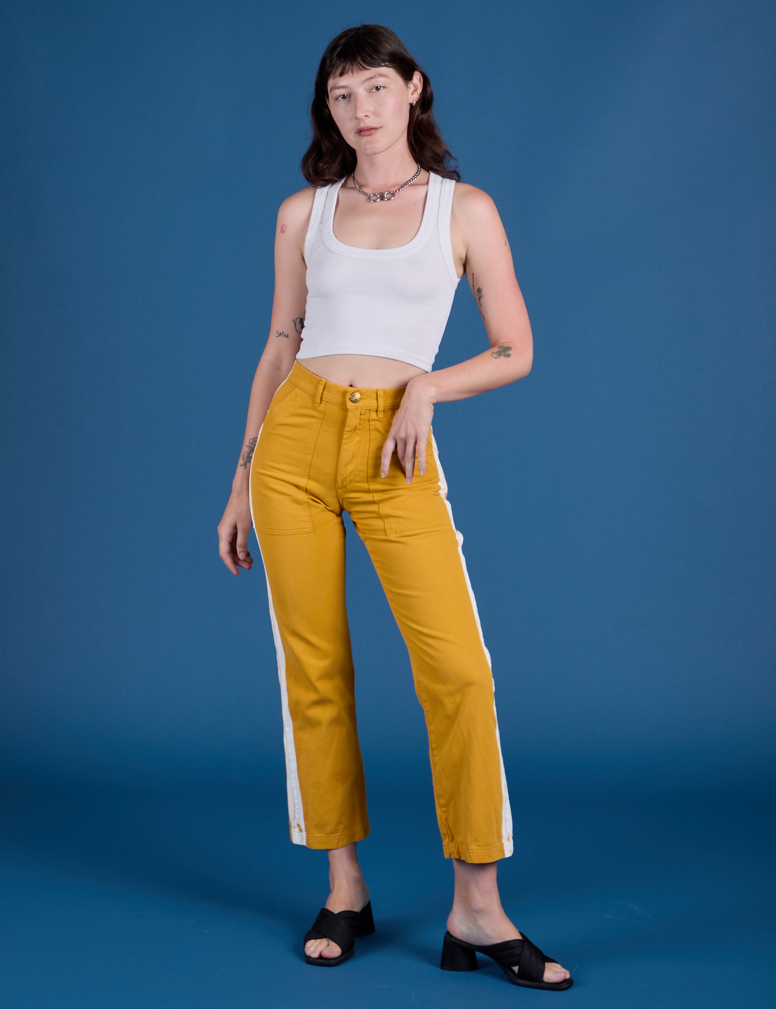 Alex is 5’8” and wearing XXS Painted Work Pants in Mustard Yellow paired with vintage tee white Cropped Tank