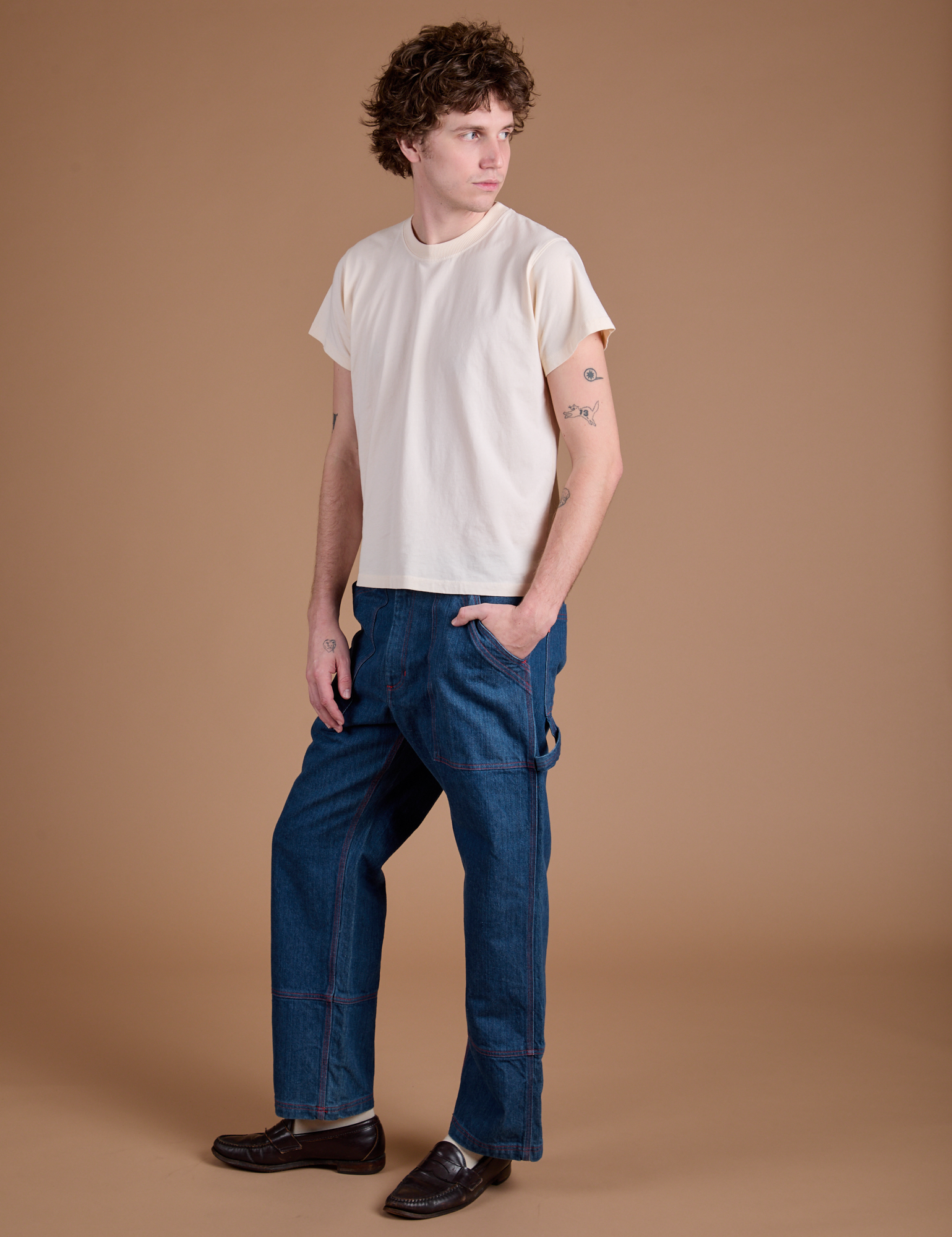 Angled front view of Carpenter Jeans in Dark Wash and Organic Vintage Tee in Vintage Tee Off-White on Quinn