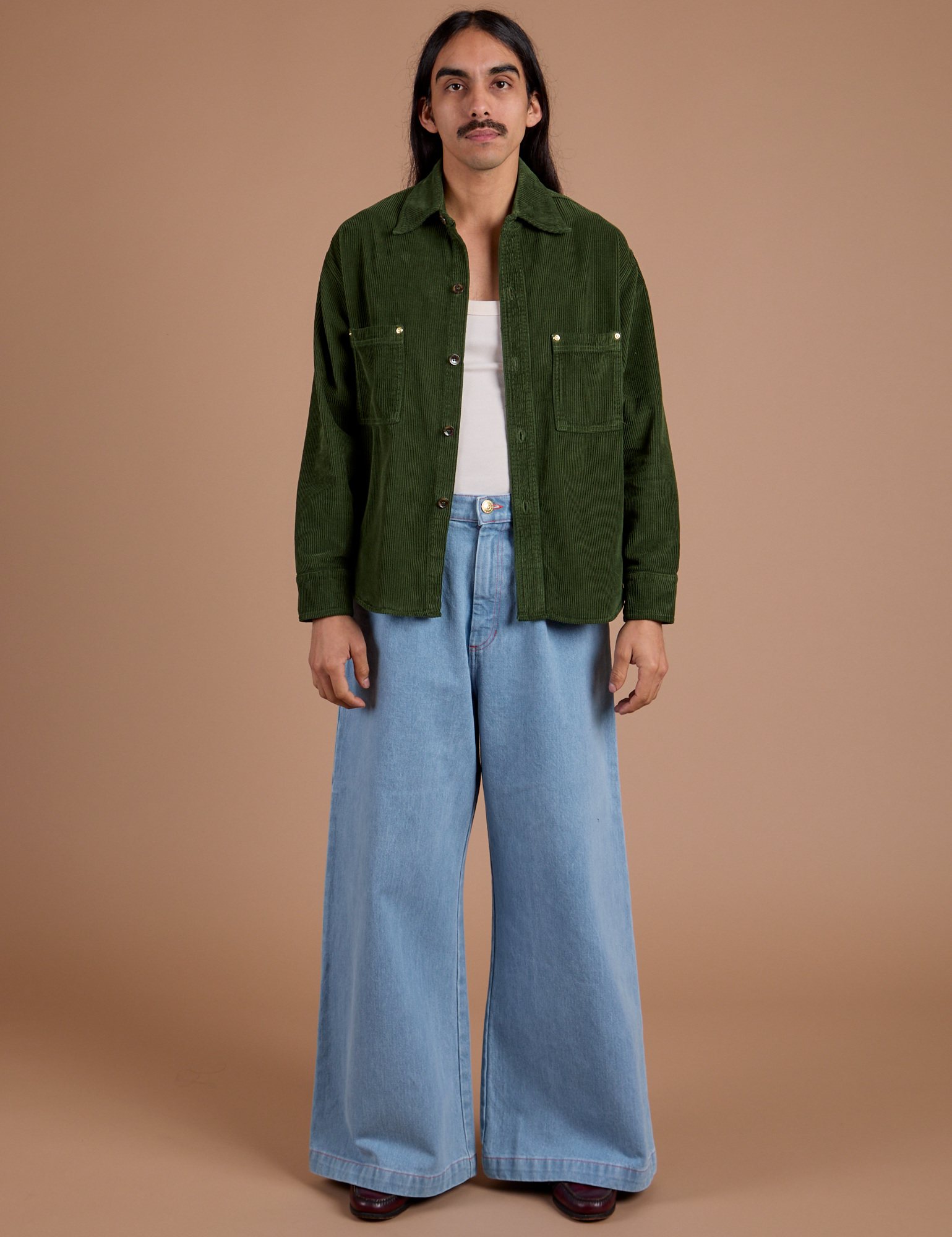 Anthony is wearing Cropped Corduroy Overshirt in Evergreen and light wash Indigo Wide Leg Trousers