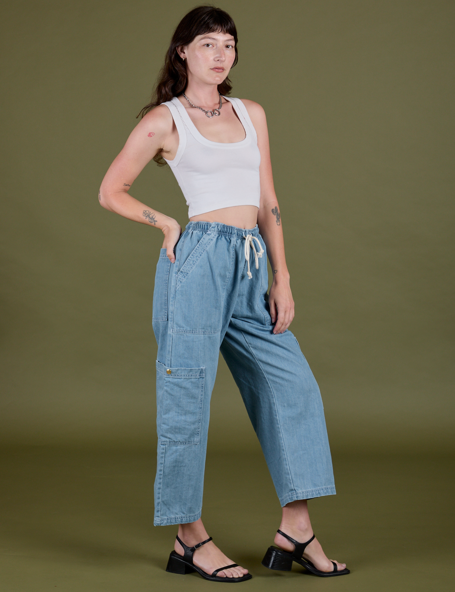 Angled front view of Denim Drop Pocket Pants in Light Wash and vintage tee white Cropped Tank on Alex