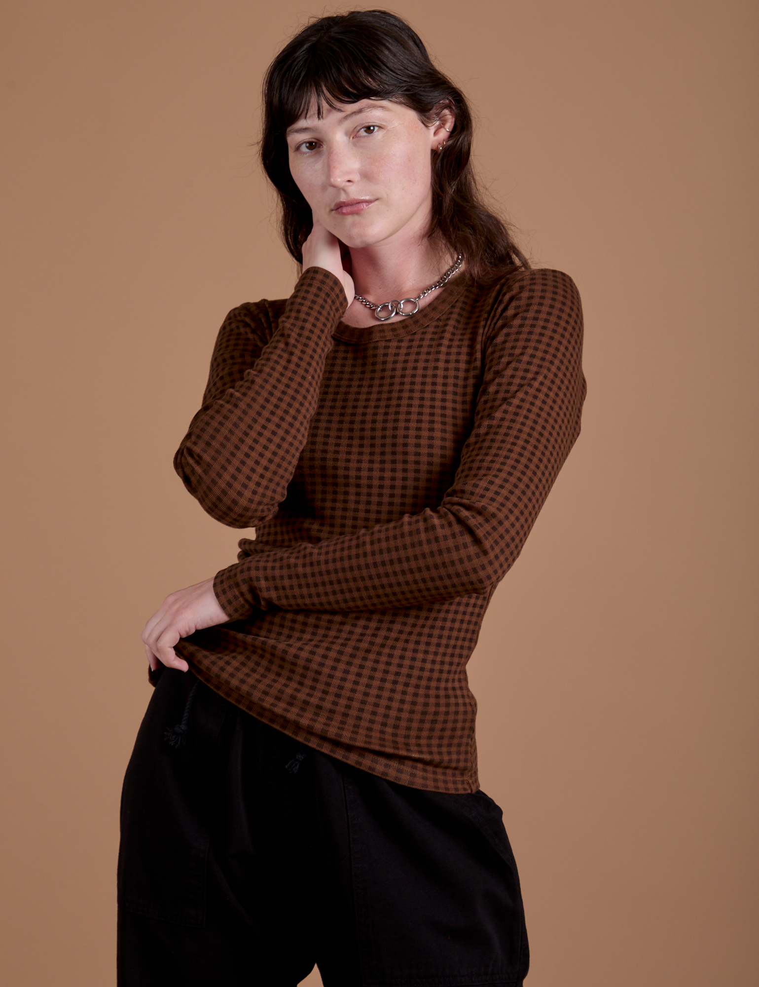 Alex is wearing Gingham Long Sleeve Baby Tee in Fudgesicle Brown