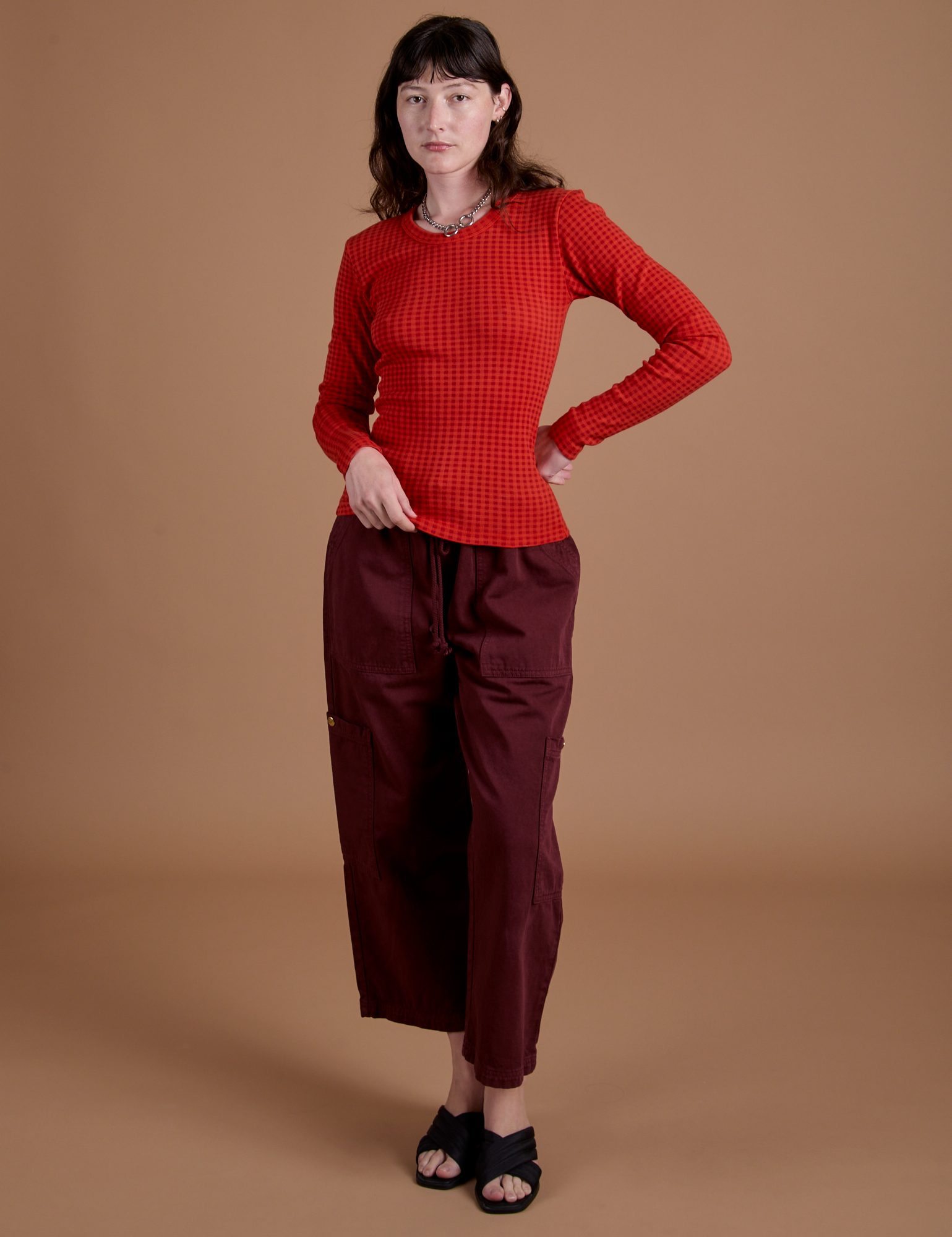 Alex is wearing Gingham Long Sleeve Baby Tee in Mustang Red paired with red wine Drop Pocket Cargo Pants